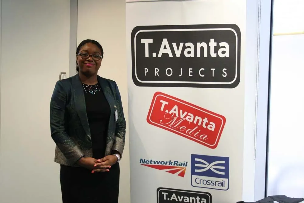A delegate stands beside a pull-up banner for T.Avanta Projects.