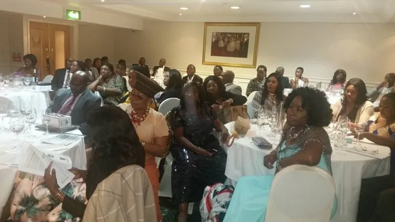 Guests in evening wear and Nigerian traditional dress seated at round banquet tables in a hotel function room.