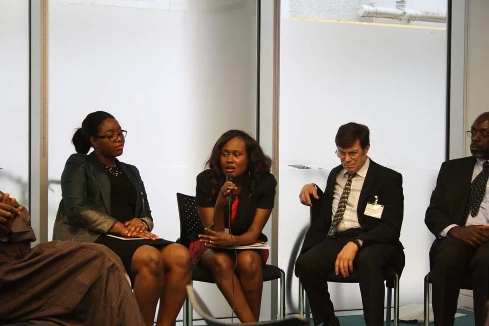 Panel members seated at the front of the room; one speaks into a microphone.