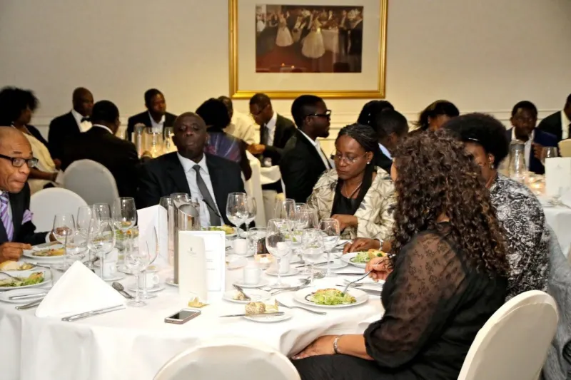 Guests dining at round tables laid with white linen, glassware and table plans.