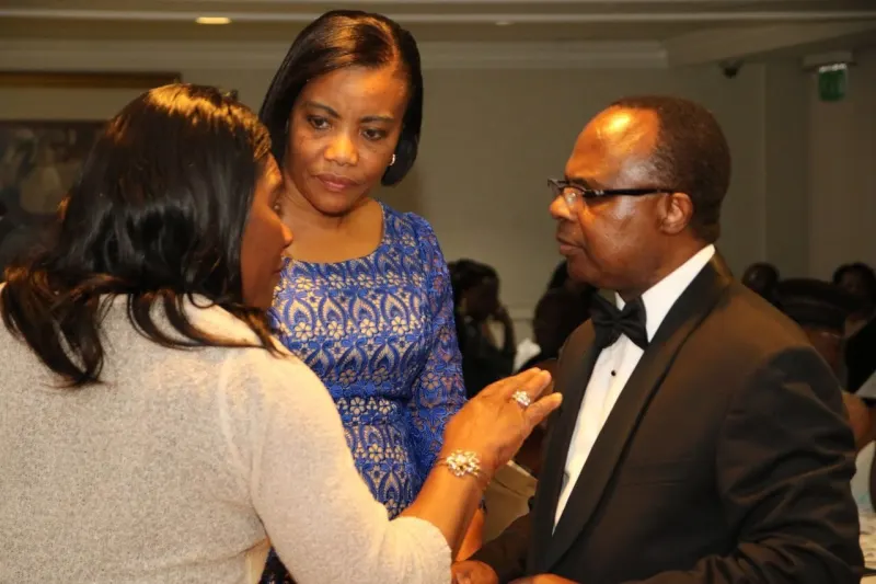 Two women and a man in black tie deep in conversation during the evening.