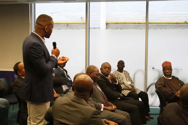 A delegate stands with a microphone to put a question to the panel while the audience listens.